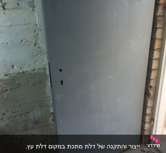 דלת מתכת אפורה על רקע קיר בטון